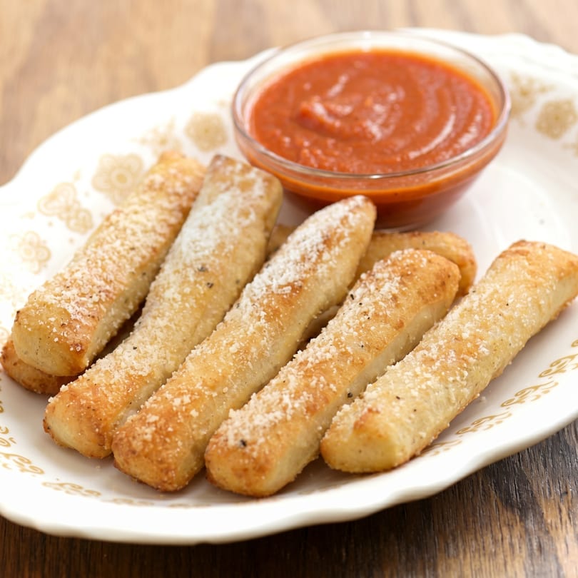 Golden-brown breadsticks sprinkled with Parmesan cheese and herbs, served with a side of marinara sauce.